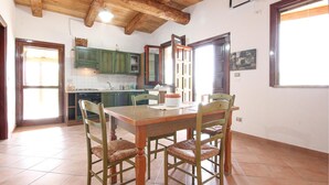 A dining area with a wooden table and four chairs, a kitchen with green cabinets, and a window with a view. - Gorgeous home in Ascea Marina with house sea view (Ascea Marina)