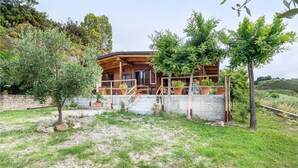 A rustic wooden house with a balcony, surrounded by greenery and a stone wall. - Gorgeous home in Ascea Marina with house sea view (Ascea Marina)