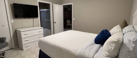 Ein Schlafzimmer mit einem Bett, einem Schminktisch, einem Fernseher und einem Deckenventilator.