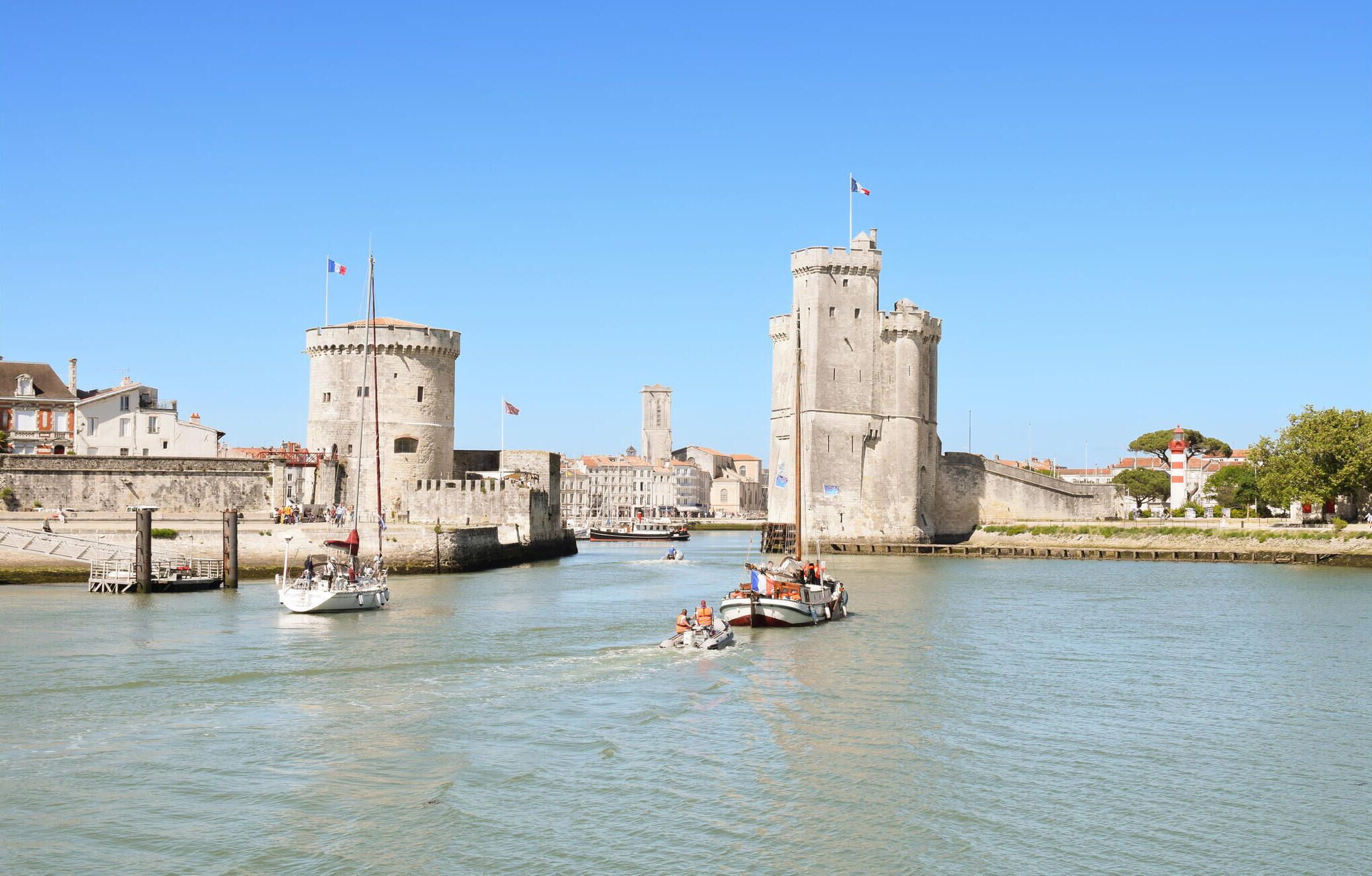 Un site historique situé au bord de l’eau, avec des fortifications en pierre, un ciel dégagé et des bateaux sur l’eau.
