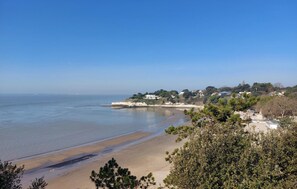 A coastal view with a sandy beach, clear blue sea, and a residential area with houses and greenery in the background. - 2 bedroom lovely home in Meschers-sur-Gironde (Meschers-sur-Gironde)