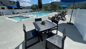 Uma área de piscina no terraço com espreguiçadeiras e guarda-sóis, mesa de bilhar e vista para as montanhas.