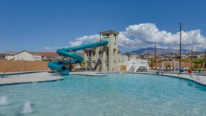 En swimmingpool med et vandrutsjebanen og en tårnstruktur i baggrunden.