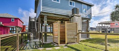 Ein zweistöckiges Haus mit einer Veranda, einem kleinen Holzgebäude und einem umzäunten Garten.
