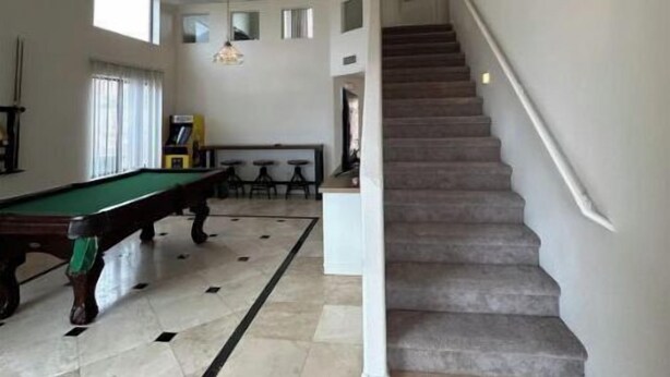 Ein geräumiges Zimmer mit Pooltisch, Treppe und Poolbereich.
