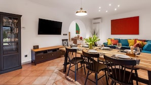A modern dining area with a wooden table, chairs, and a TV mounted on the wall.
