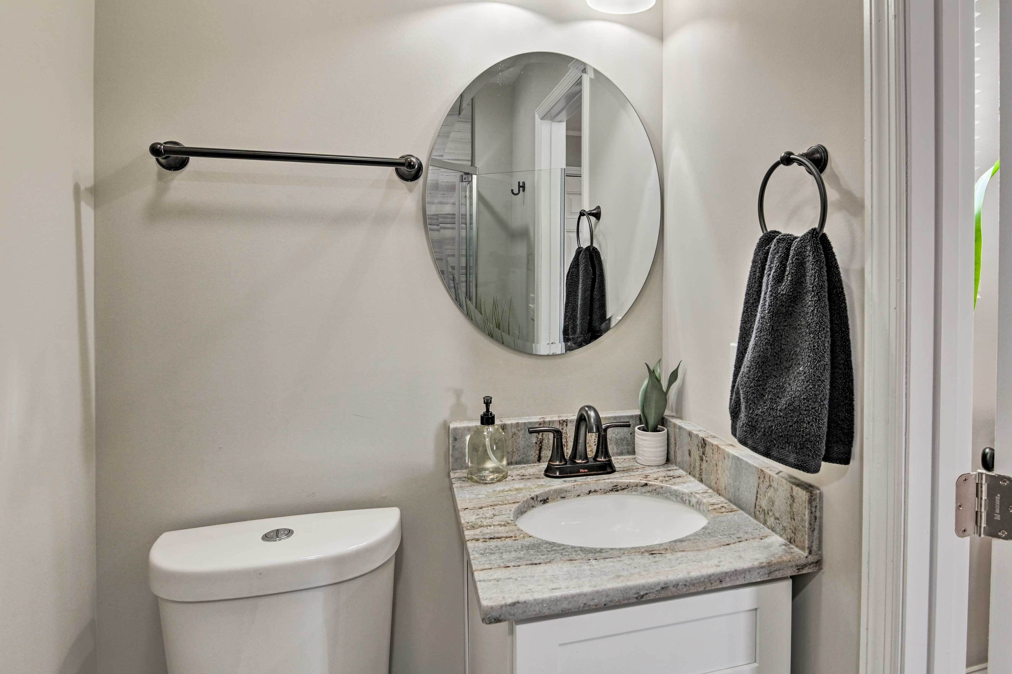 A bathroom with a toilet, sink, mirror, towel ring, and towel rack.