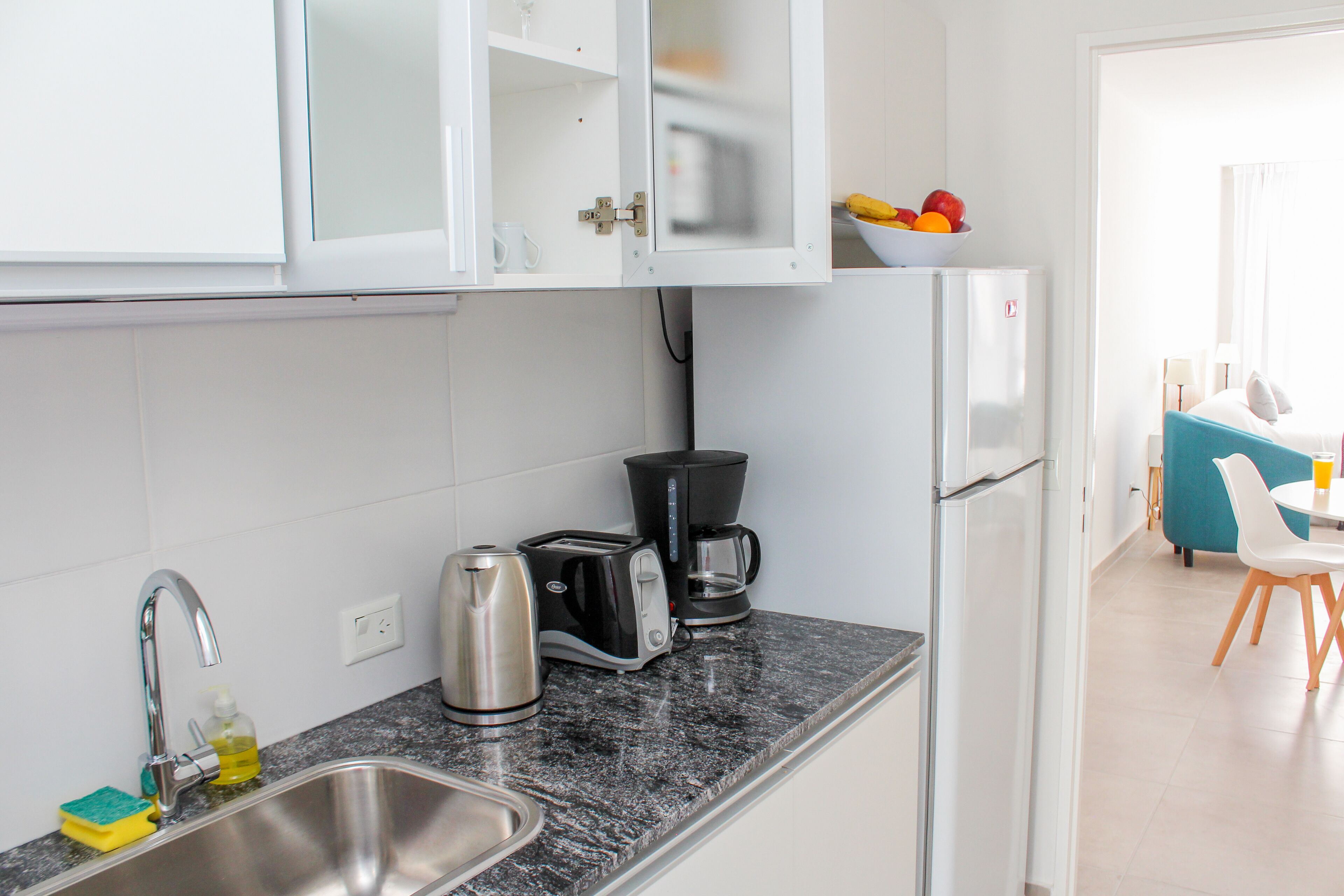 A modern kitchen with a sink, a coffee maker, a toaster, and a refrigerator.