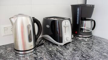 A kitchen counter with a kettle, toaster, and coffee maker.