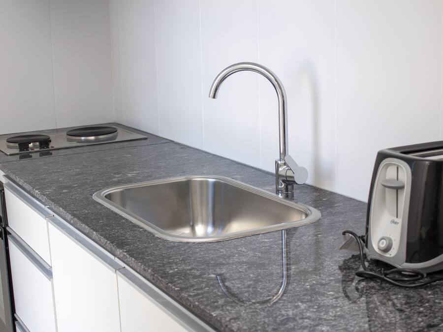 Een keuken met een roestvrijstalen spoelbak, een broodrooster en een fornuis.