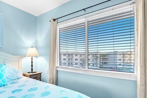 Enjoy a restful stay in this cozy room with a large window, comfortable bed, and convenient bedside table.