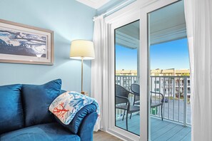 Relax on the balcony with a view of the surrounding buildings, featuring a sofa, floor lamp, and artwork.