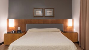 A hotel room with a large bed, wooden headboard, two bedside tables with lamps, a telephone, and a desk with a laptop. - DELPLAZA Timbiras São Paulo (São Paulo)