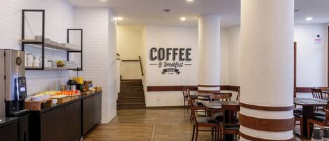 Een moderne koffie- en ontbijtruimte met een bord, houten vloeren en een buffetopstelling.