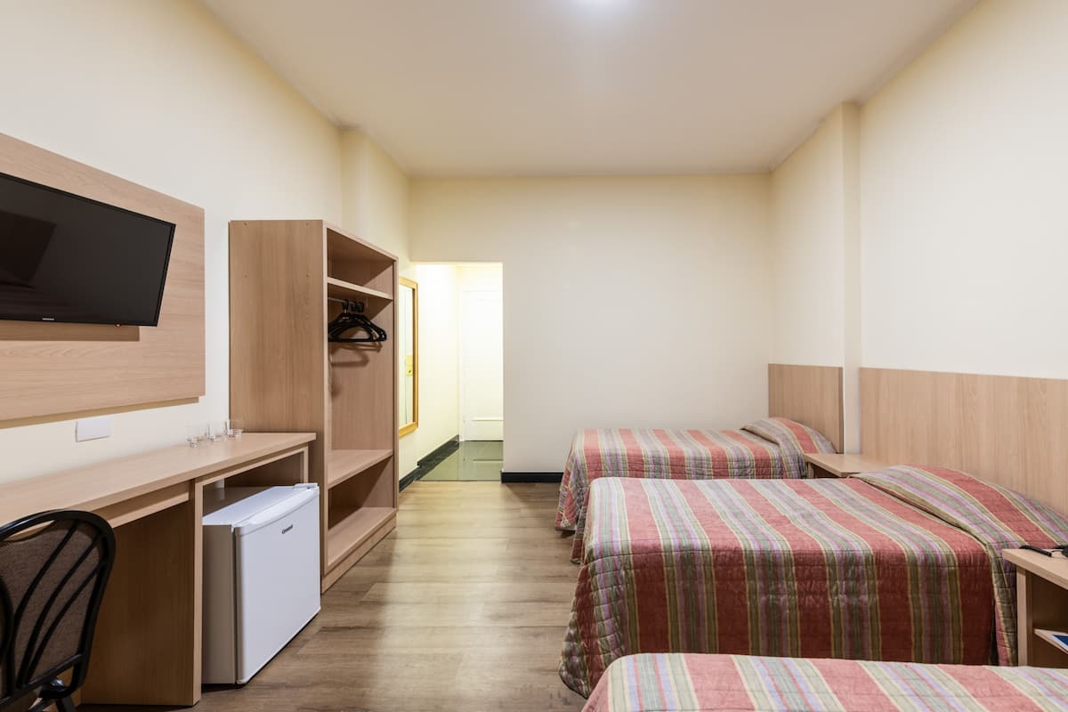 A hotel room with a bed, a desk, a TV, and a wardrobe.