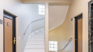 A clean, modern hallway with a white staircase, beige walls, and a marble accent wall. - DELPLAZA Timbiras São Paulo (São Paulo)
