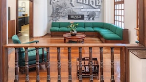 A room with a green sofa, a wooden railing, and a bicycle mounted on the wall. - DELPLAZA Timbiras São Paulo (São Paulo)