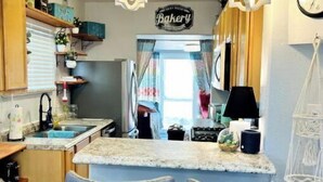A kitchen with two blue bar stools, a hanging light fixture, and a 'Bakery' sign.