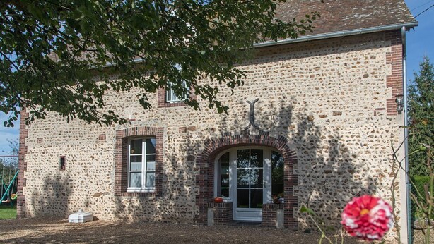 Un bâtiment en pierre doté d’une entrée centrale en forme d’arche et d’une petite fenêtre sur le côté gauche.