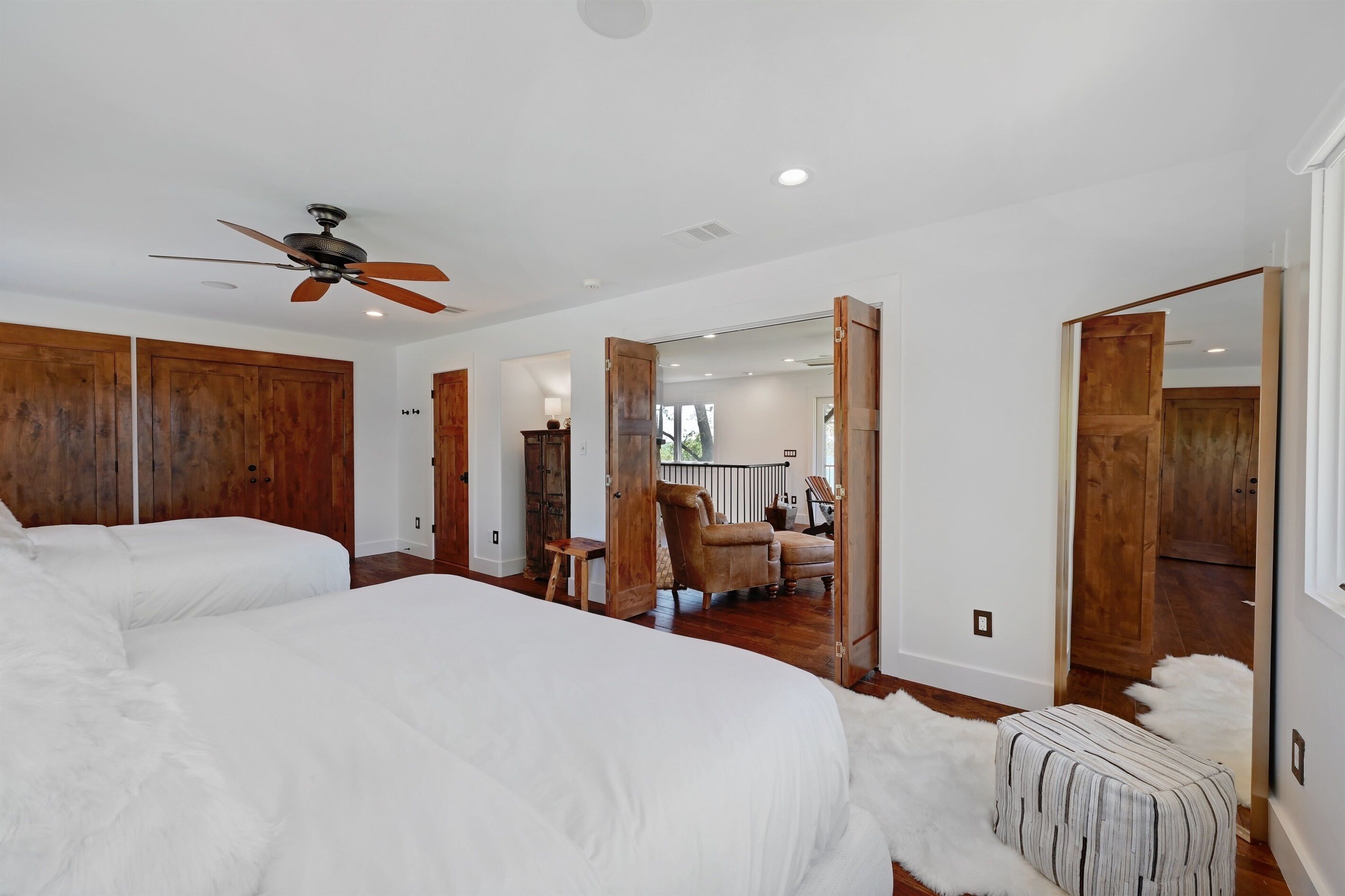 A bedroom with a large bed, wooden wardrobe, and a ceiling fan.