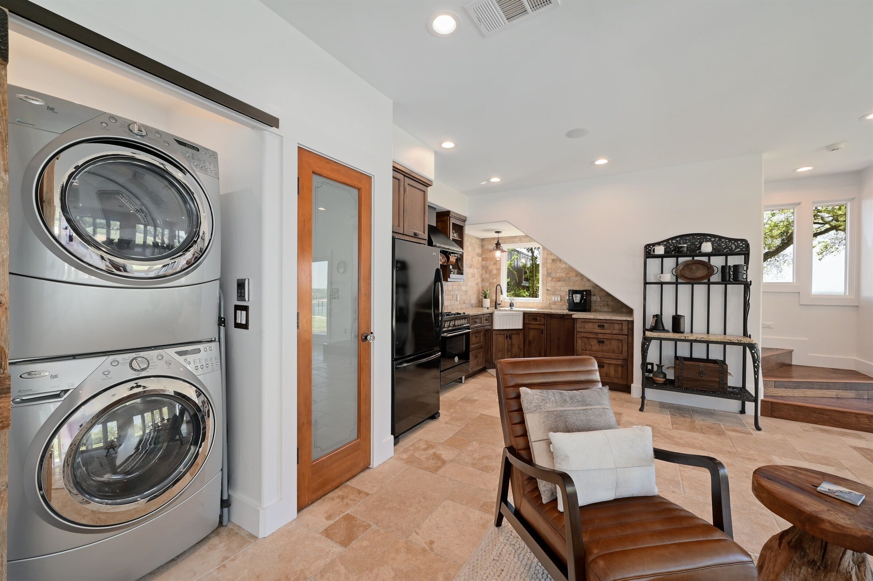 A modern kitchen with stainless steel appliances, a wooden dining area, and a built-in washer and dryer.