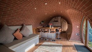 A cozy kitchen with a brick arch ceiling, a wooden bar area, and a seating area with a sofa and cushions.