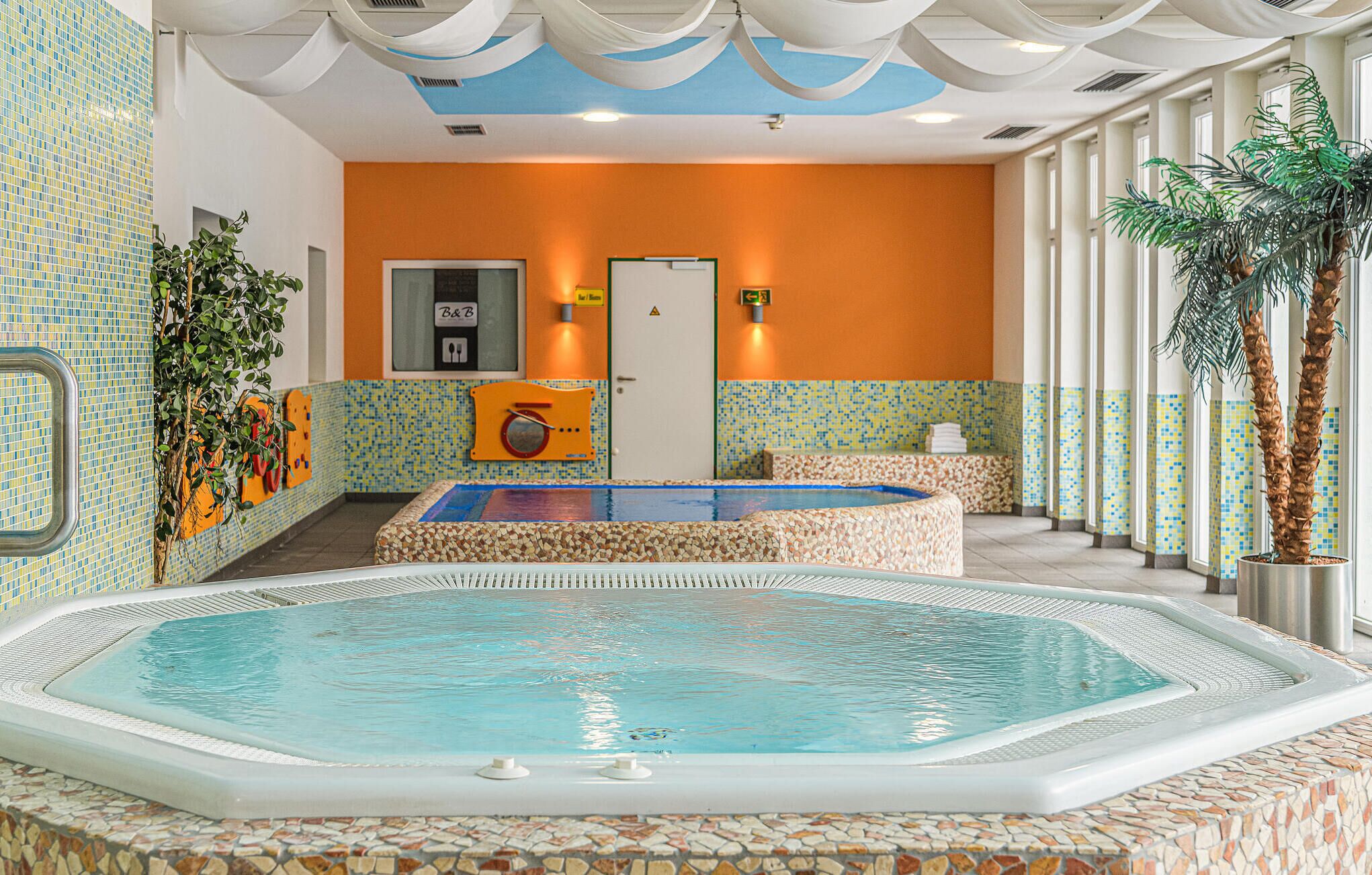 A hotel lobby with a large indoor pool, a reception desk, and a door marked "B&B".