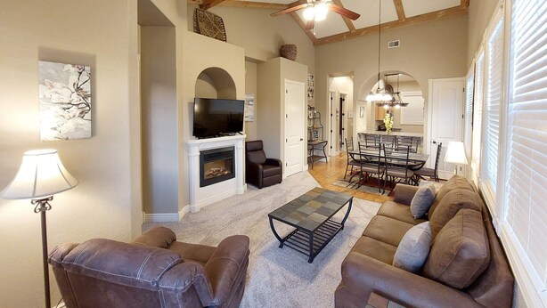 A spacious living room with a fireplace, a television, and a dining area with a chandelier. - Paradise Cove Walk-in Log Cabin by Silver Dollar City & Table Rock Lake! (Branson)