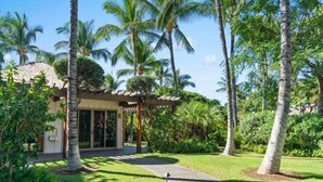 A resort with a covered outdoor area, palm trees, and a building with a tiled roof.