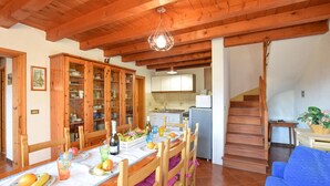 Un coin repas avec des meubles en bois, une cuisine à l’arrière-plan et un escalier menant à l’étage.