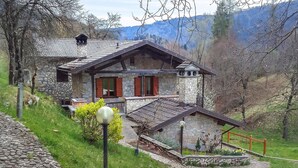 Une maison en pierre avec un toit en pente, un balcon et un petit porche.