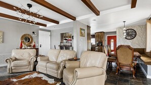 A spacious living room with leather sofas, a dining area, and a kitchen in the background. - Stylish Chalet with Hot Tub and Jacuzzi! (Lake Arrowhead)