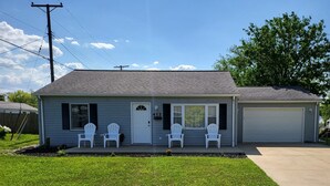 Une maison de plain-pied avec un porche à l’avant, un garage et une pelouse bien entretenue.