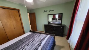 Une chambre à coucher avec un lit, une commode, un miroir et un mur sur lequel est écrit : « Doux rêves ».