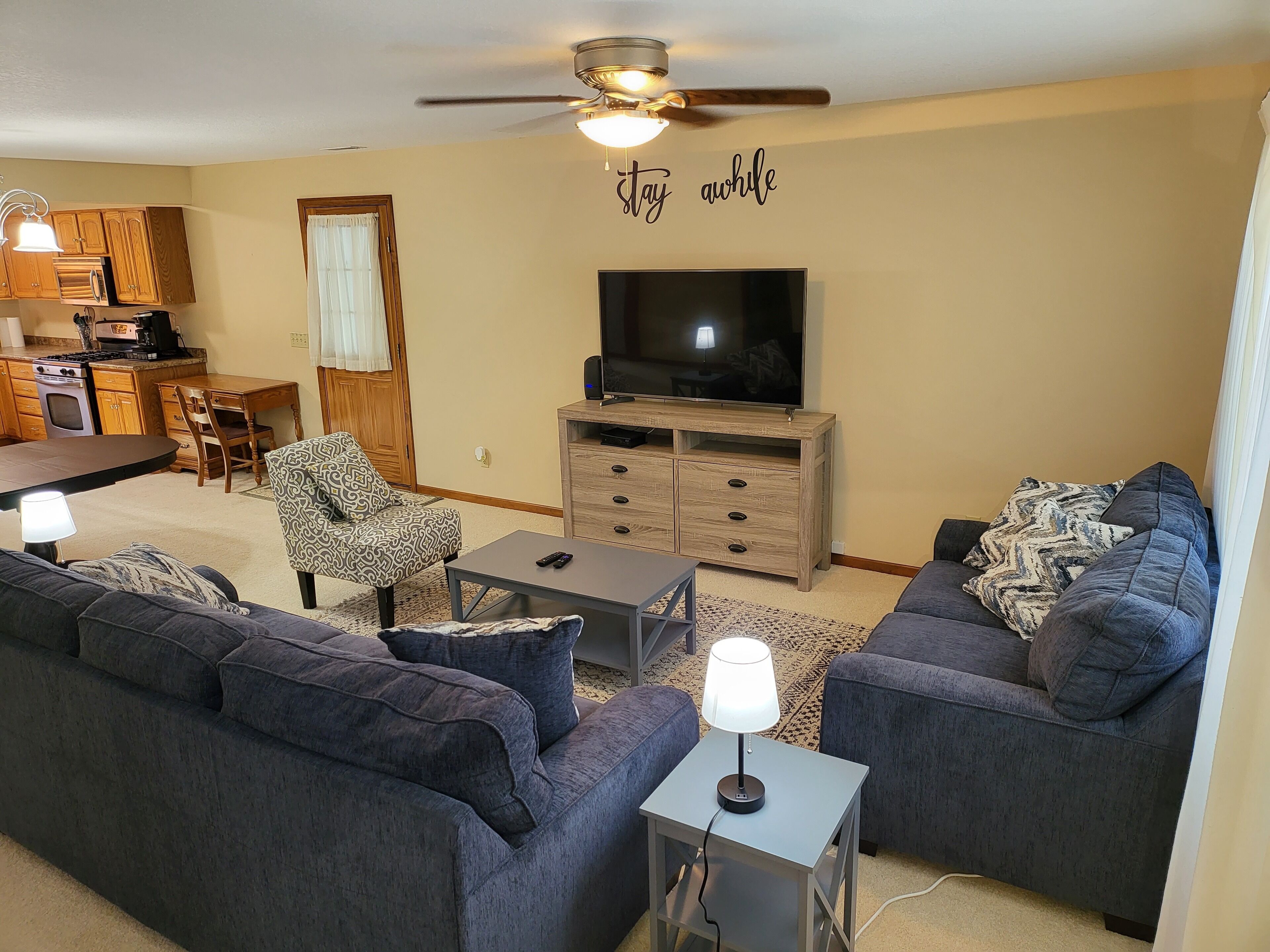 A living room with a TV, sofas, a coffee table, and a ceiling fan.