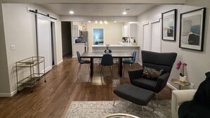 Una sala de estar moderna con comedor, una cocina al fondo y un pasillo que conduce a otra habitación.