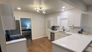 Una cocina moderna con armarios blancos, una isla central y piso de madera.