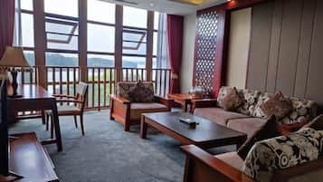 Una habitación con sofá, sillas, una mesa de centro, lámpara y vistas amplias a través de grandes ventanas.