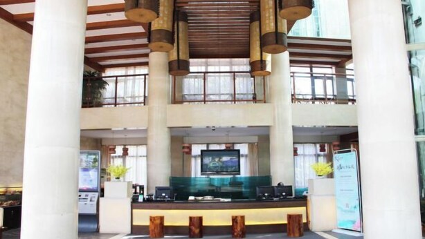 A hotel lobby with a reception desk, large columns, and a high ceiling with wooden beams. - Longshui Lake Dalong Bay Hotel (Chongqing)
