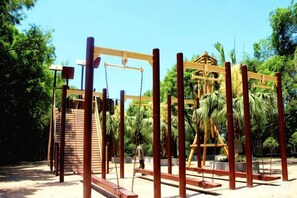 Un patio de juegos al aire libre con diversas estructuras de escalada y columpios.