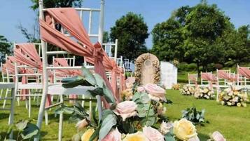 Een trouwlocatie met rijen stoelen, bloemdecoraties en een centrale boog.