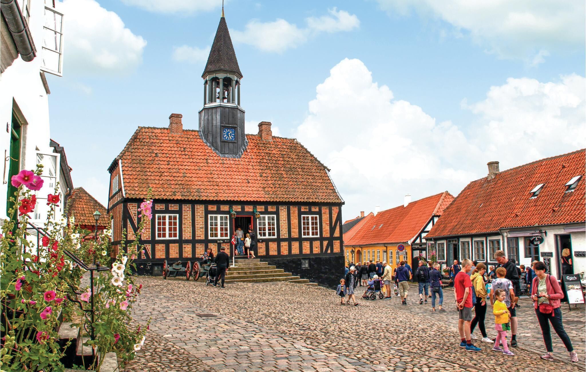Une rue pavée menant à un bâtiment traditionnel surmonté d’une tour horloge, entouré d’autres bâtiments historiques.