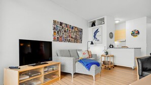 Ein modernes Wohnzimmer mit einem Flachbildfernseher, einem grauen Sofa, einer Holz-TV-Konsole und einer Wandcollage.