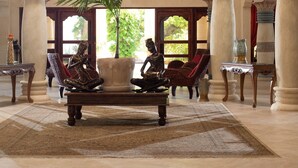 A grand lobby with high ceilings, ornate columns, and a central seating area with a large potted plant. - Gorgeous Balaji Palace with Private Beach (Río San Juan)