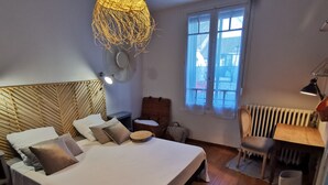Ein Schlafzimmer mit einem großen Bett, einem kleinen Tisch, einem Stuhl, einem Heizkörper und einem Fenster.