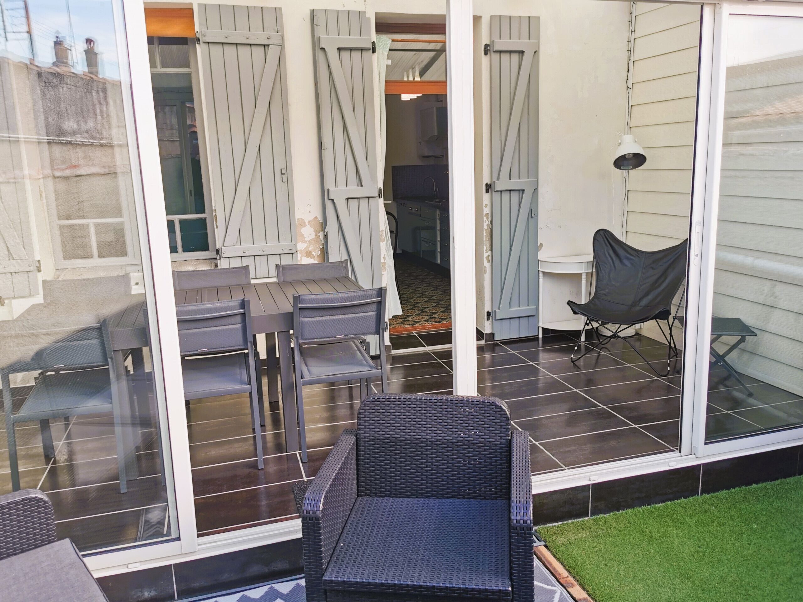A patio area with a table and chairs, a folding chair, and a small table.