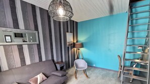 Ein modernes Wohnzimmer mit grauem Sofa, einem Holztisch, einer Stehlampe und einer blauen Akzentwand.
