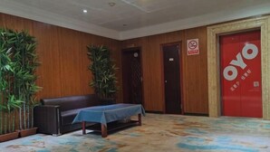 A room with a wooden wall, a sofa, a table with a blue tablecloth, and a red door with the word "OYO" on it.