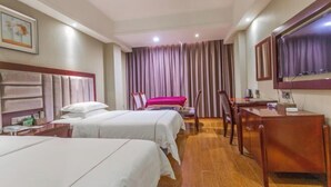 A hotel room with two beds, a desk, a chair, a TV, and a window with curtains.