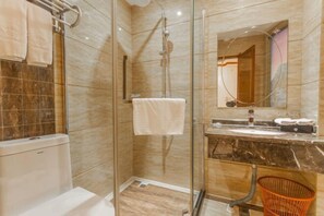 A modern bathroom with a glass shower enclosure, a marble countertop, and a visible toilet. - Wanhao Holiday Hotel (Dao County)